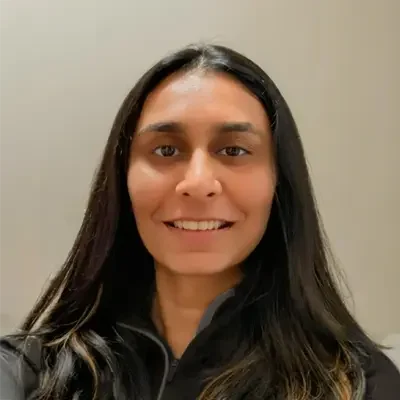Bhakti Sudani smiling at the camera while wearing a black zip-up jacket.